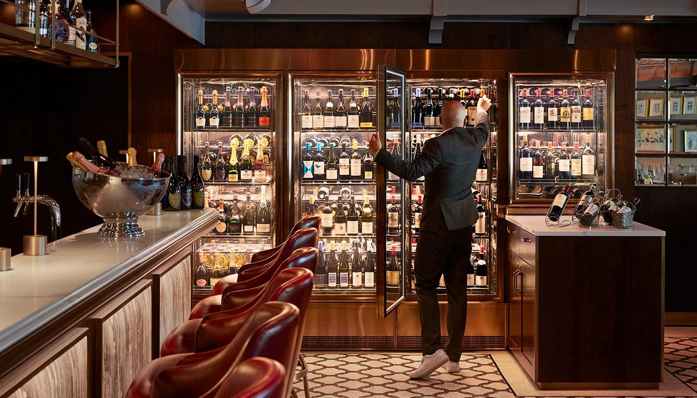 Mann im Anzug nimmt sich eine Flasche Wein aus dem Kühlschrank im Restaurant in der Düsseldorfer Altstadt