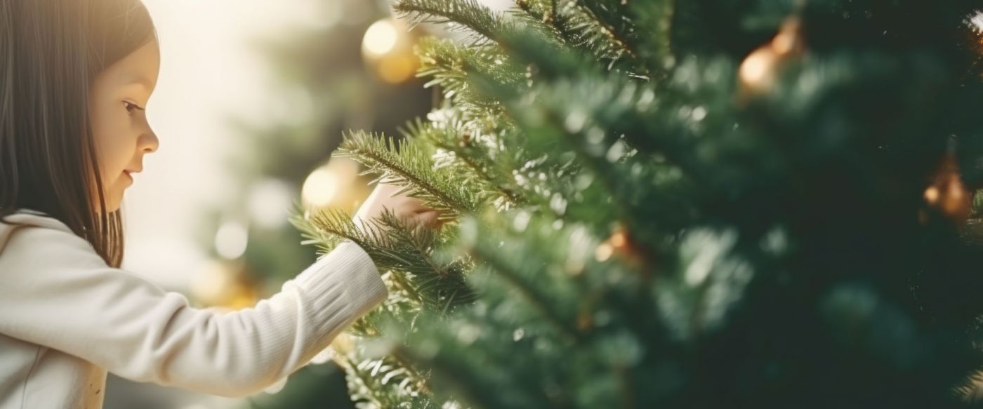 Ein Mädchen schmückt einen Tannenbaum