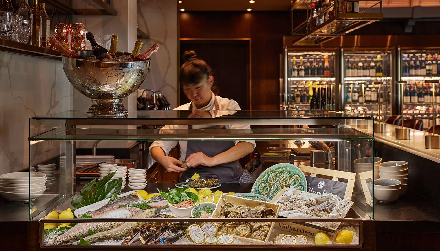 Frau steht hinter einer gläsernen Auslage mit Fisch und Meeresfrüchten im Restaurant in der Düsseldorfer Altstadt