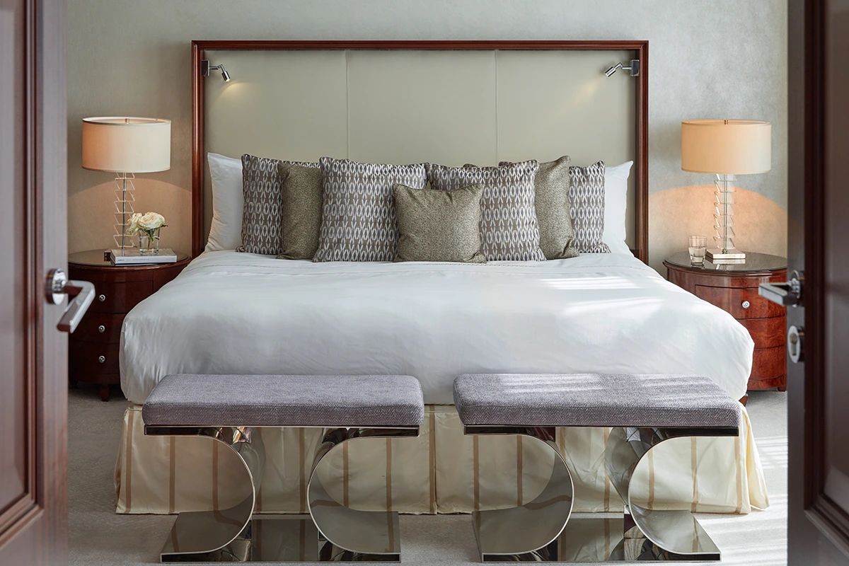 Blick auf ein großes Doppelbett mit vielen Kissen und zwei Beistelltischen