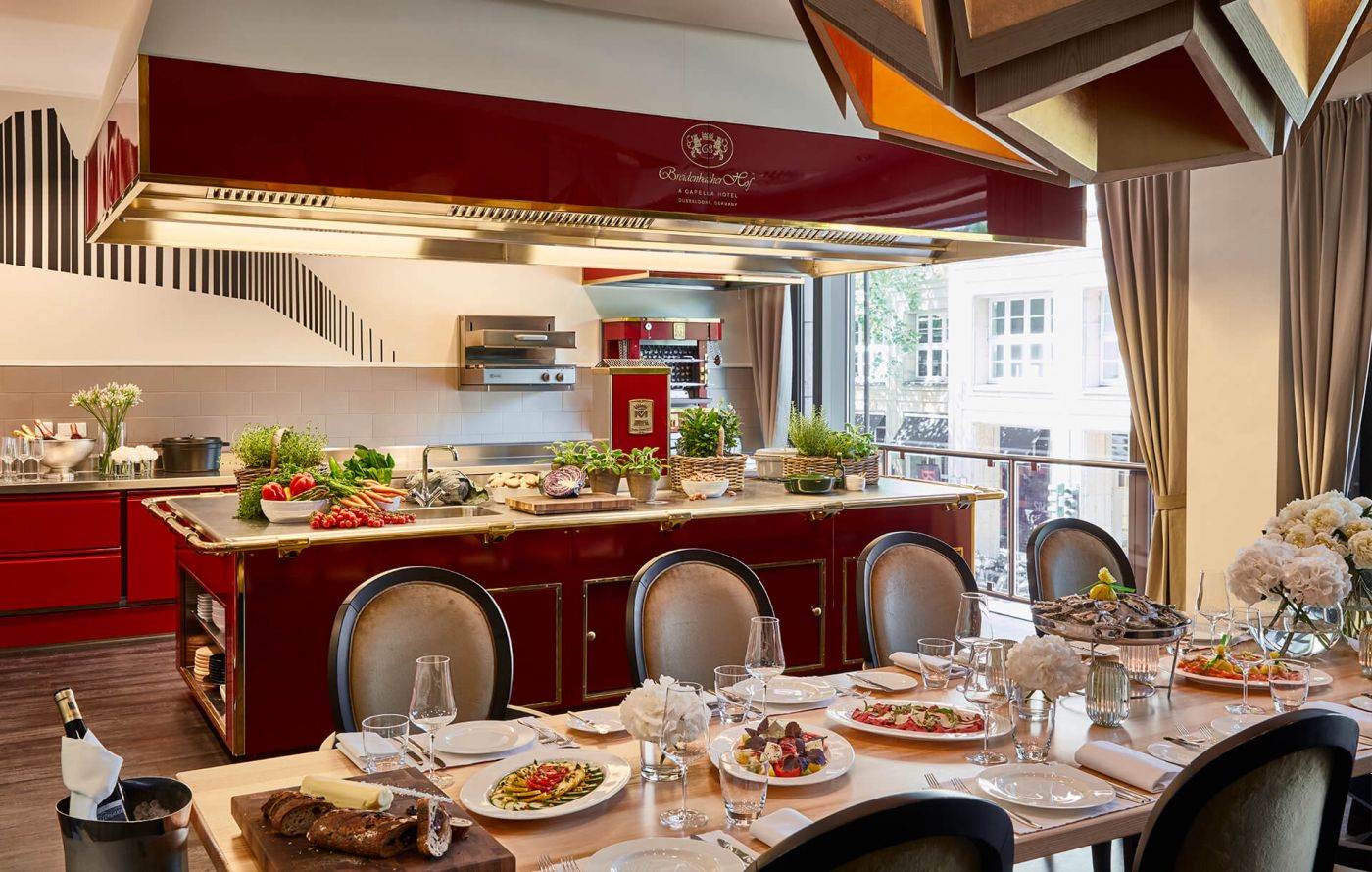 Lange Tafel vor einer roten Showküche in der Eventlocation in Düsseldorf