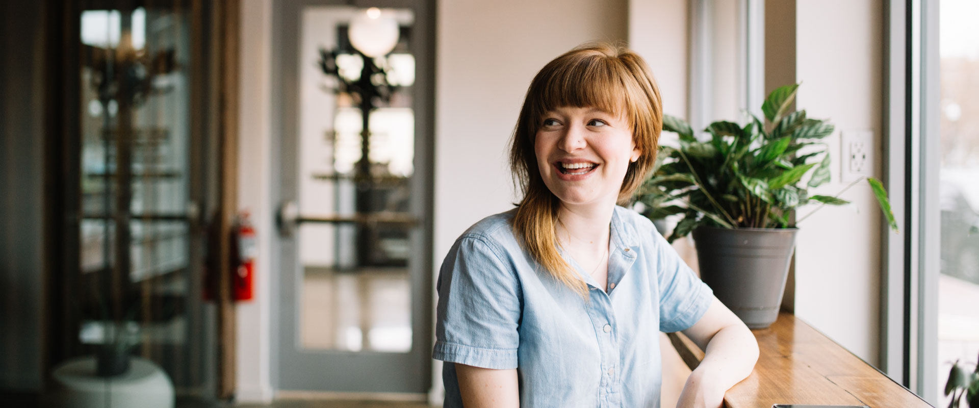A smiling woman leans against a bar table
