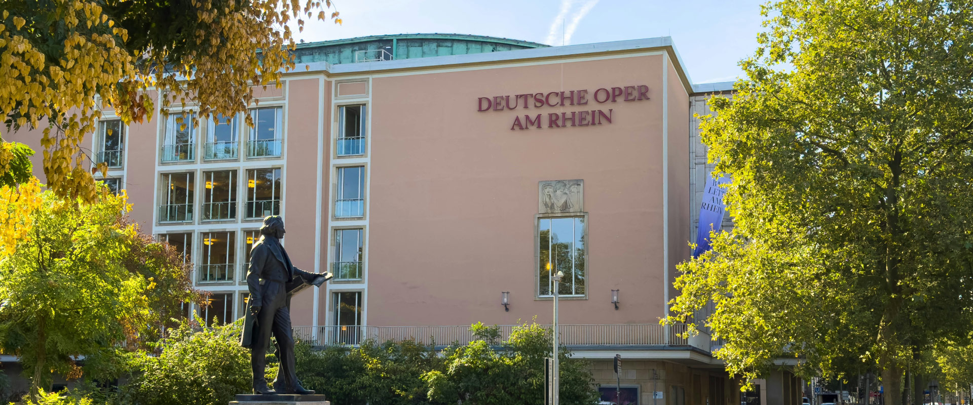 Deutsche Oper am Rhein in Düsseldorf with a monument and surrounding greenery