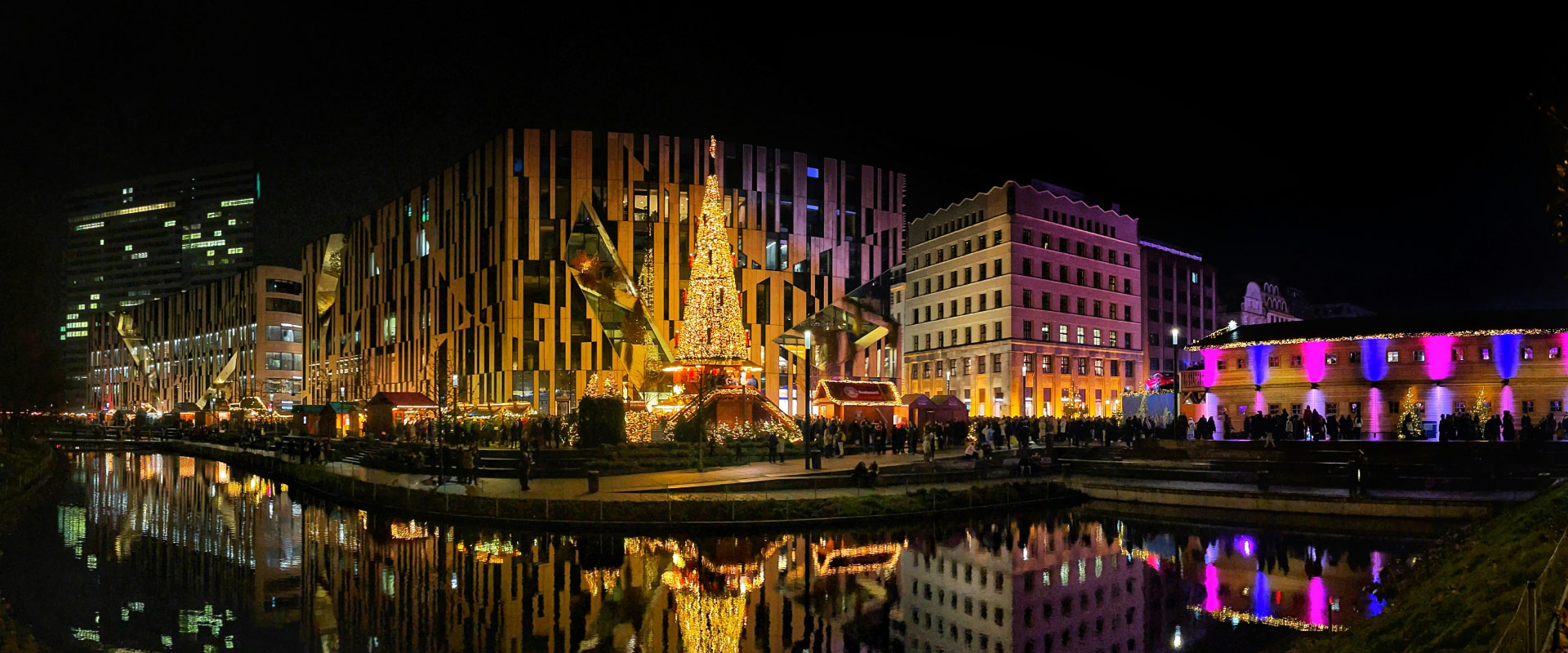 Illuminated Christmas market in central Düsseldorf at night with a large Christmas tree by the water